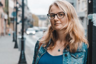 A blonde woman with glasses in a jeans jacket